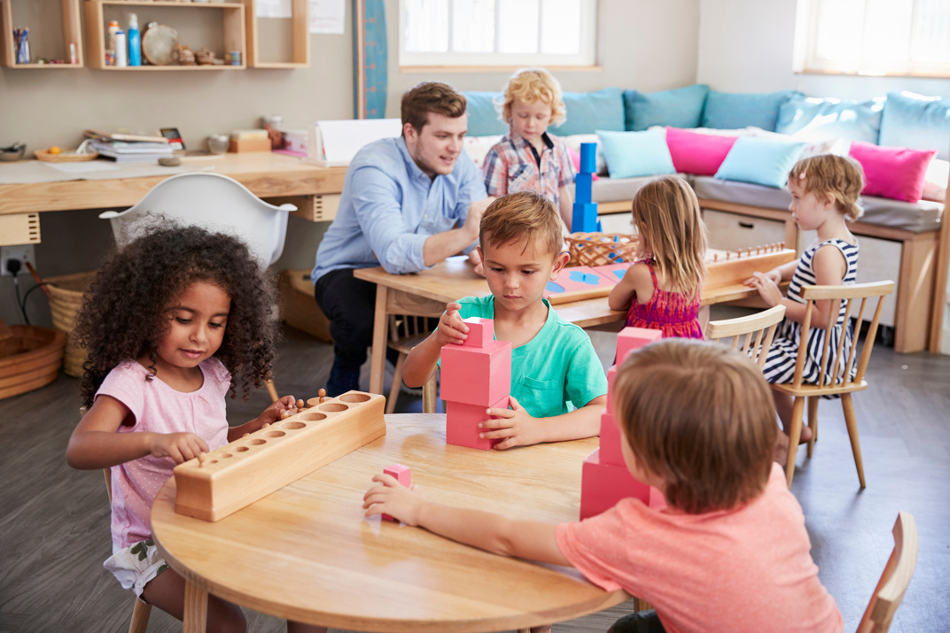 Teacher and Pupils Working at Tables in Montessori School