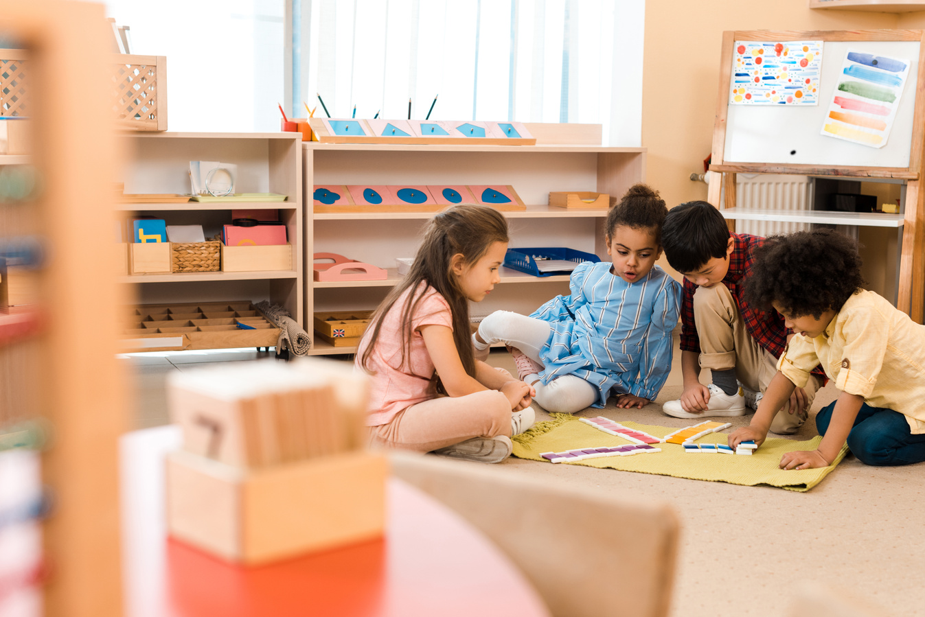 Selective focus of children playing game on floor in montessori school